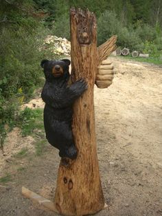 a statue of a bear climbing on a tree trunk with his paw in the air