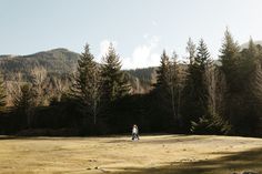 a person walking through a field with trees in the background