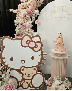 a hello kitty birthday cake with pink flowers on it and a sign that says happy birthday morgan