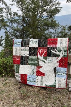 a quilt made to look like a deer on the side of a road with trees in the background