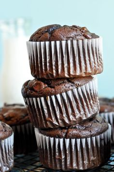 chocolate muffins stacked on top of each other next to a glass of milk