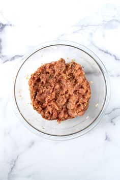 a glass bowl filled with food on top of a marble counter