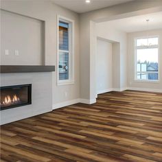 an empty living room with wood flooring and a fire place in the fireplace area