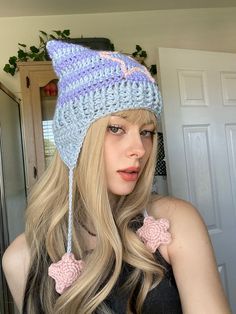 a woman with long blonde hair wearing a crocheted hat and bow tie is looking at the camera