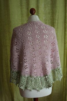 a pink and green crocheted shawl on top of a mannequin