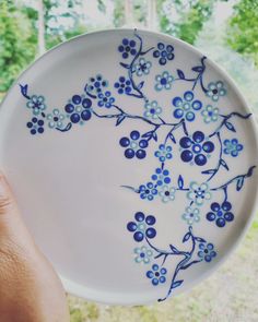 a person holding a plate with blue flowers on it