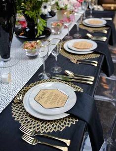 the table is set with black and gold place settings