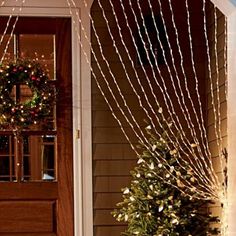 a small christmas tree sitting in front of a door with lights on the outside and inside