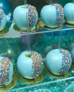 there are many blue apples with sprinkles on them in the display case