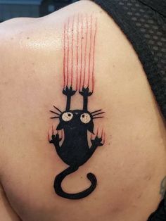 a cat tattoo on the back of a woman's left shoulder, with red streaks coming out of its eyes