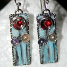 These Earrings Are Hand Enameled On Pewter Blanks. They Have A Light Blue Background With Silver Dish Circles Filled With Lavender And Yellow Enamel And A Red Crystal Gem In The Tallest Flower. They Hang 1 7/8" Long From The Ear Lobe By Nickel Free French Wires. They Are Boho Chic And Fun To Wear. My Pieces Arrive In A Gift Box With My Card Ready For Gift Giving Or As A Special Treat For Yourself. Thank You For Stopping By My Pm Boutique The Moon Cradle Studio - Enjoy And I Hope You Visit Often! Enamel Jewelry Necklaces, Blue Enamel Flower Earrings As Gift, Silver Enamel Flower Earrings As Gift, Silver Enamel Flower Earrings For Pierced Ears, Silver Flower Enamel Earrings, Silver Flower Earrings With Enamel For Pierced Ears, Moon Cradle, Torch Fired Enamel Jewelry, Tall Flowers