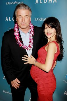 a woman in a red dress and a man in a black suit posing for the camera