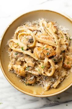 a bowl filled with pasta covered in sauce and parmesan cheese on the side