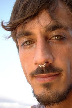 a close up of a man with a nose ring