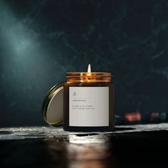 a candle that is sitting on the floor in front of a dark background with light coming from it