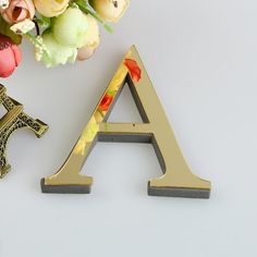 the letter a is next to a vase with flowers and a small brooch on it