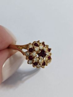 Gorgeous Garnet Ring-  gemstone- with dazzling crystals.  It shines like real gold. GREAT Gift! No Tarnish Size 6 1/2 Gemstones: #1 - Garnet color CZ's, square diamond shape 3 X 3mm, faceted  #2 - White CZ's, round 1.2mm, faceted  It will come in a gift bag. Gold Ruby Cluster Ring, Gold Ruby Flower Ring, Gold Birthstone Cluster Ring, Gold Cluster Ring With Birthstone, Gold Cluster Ruby Promise Ring, Gold Cluster Ruby Ring For Promise, Gold Cluster Ruby Jewelry, Gold Ruby Cluster Jewelry, Cluster Ruby Rings In Gold