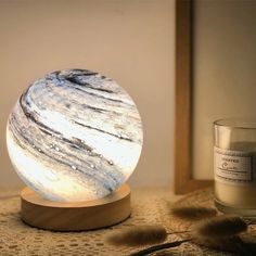 a white and black marble ball sitting on top of a wooden stand next to a candle