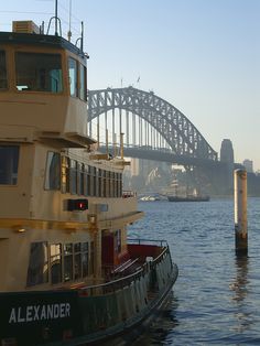 a large boat floating on top of a body of water next to a tall bridge