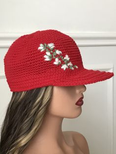 a woman wearing a red hat with white flowers on the brim and one side