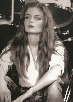 a woman with long hair sitting in front of a drum set