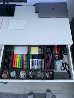 an office desk with several compartments containing pens, pencils, and other items on it