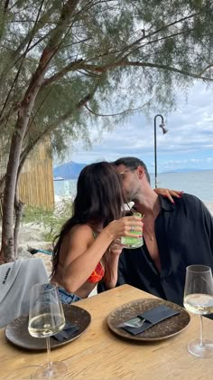 a man and woman kissing while sitting at a table