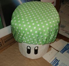 a green and white polka dot covered mushroom sitting on top of a cardboard box next to boxes