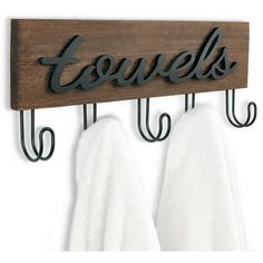 two towels hanging from hooks on a wooden sign that says, equiels and is hung on the wall