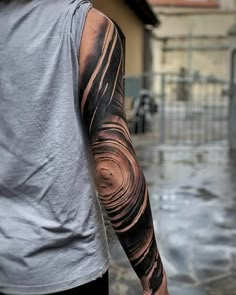 a man with a black and grey tattoo on his arm