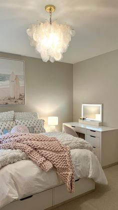 a bedroom with a bed, desk and dresser in it's corner area that has a chandelier hanging from the ceiling