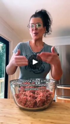 a woman standing in front of a glass bowl filled with ground meat and pointing to the camera