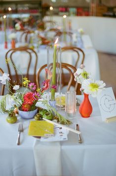 the table is set with flowers, candles and place cards for guests to sit at