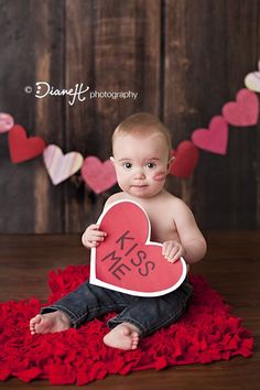 a baby is holding a heart shaped sign