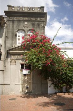 an old building with red flowers growing on it's front door and side entrance