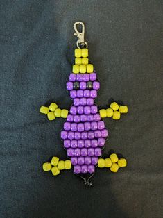 a keychain made out of legos on a black surface with yellow and purple beads