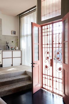 an open door leading to a living room with stairs and potted plants on the wall