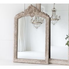 an ornate white mirror with chandelier hanging from it's sides and a vase on the other side