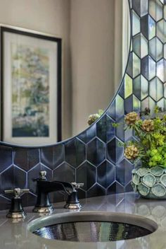 a bathroom sink sitting under a mirror next to a vase with flowers on top of it