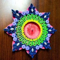 an ornament made out of paper and scissors on a wooden table with a candle in the center