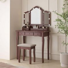 a vanity table with stool and mirror in a white room next to a potted plant