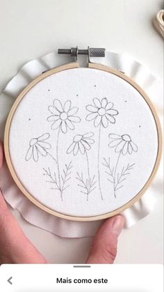 someone is holding up a hand embroidered flower