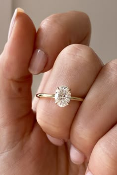 a woman's hand holding an engagement ring with a diamond in the middle and a gold band around it