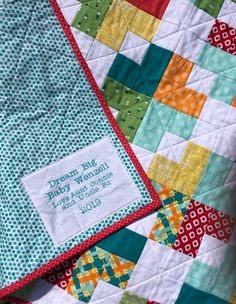 a close up of a patchwork quilt with a name tag on the front and bottom