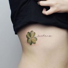 a woman's stomach with a four leaf clover tattoo on her left side ribcage