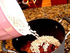 a person pouring milk into a pan filled with food