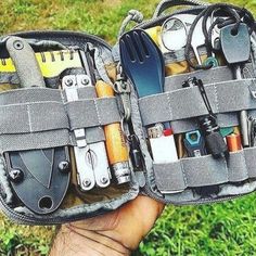 an open tool bag filled with tools on top of a grass covered field next to a person's hand