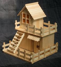 a wooden dollhouse with stairs and railings on the bottom floor, in front of a black background