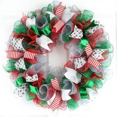 a christmas wreath with red, green and white bows on the front is displayed for sale