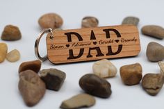 a wooden keychain with the word dad engraved on it surrounded by rocks and stones